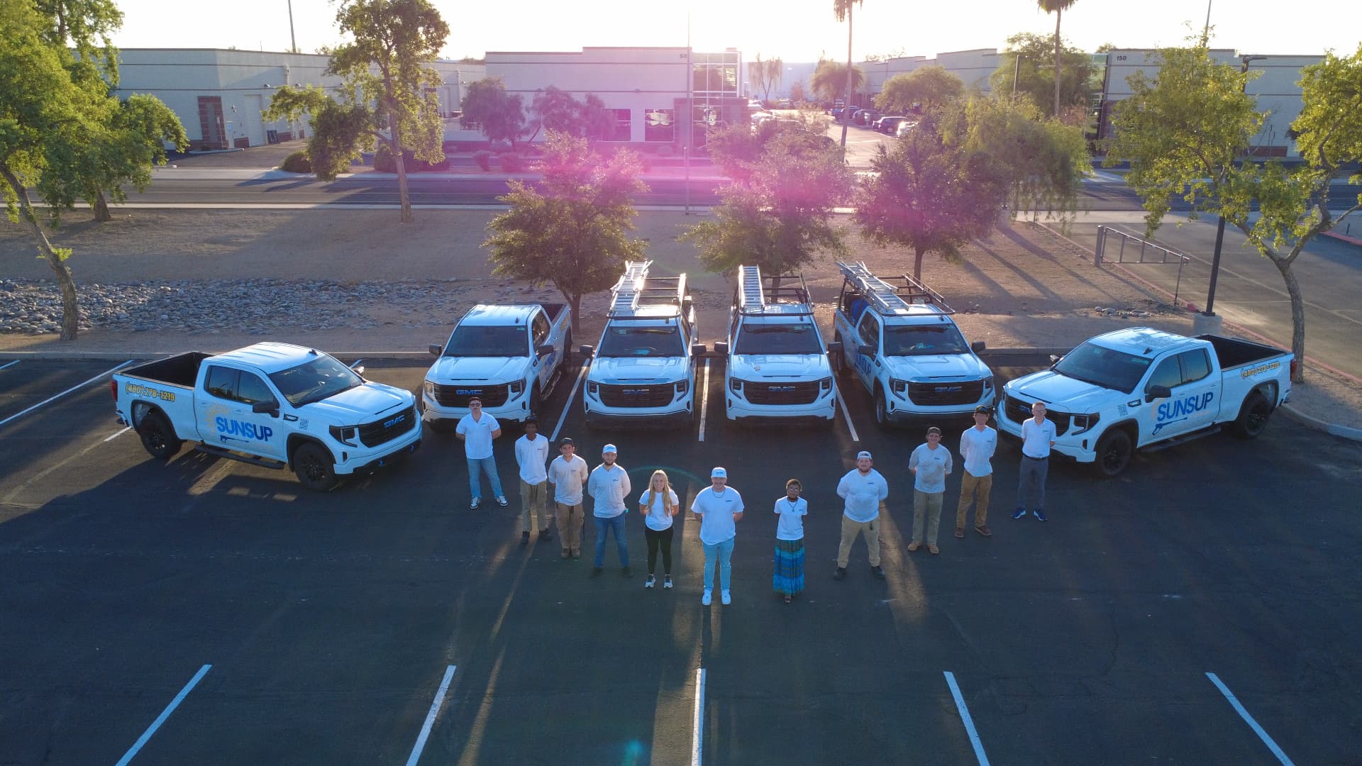 The SunsUp team standing with their fleet of branded service trucks in Arizona