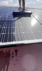 Technician washing solar panels with deionized water on a rooftop