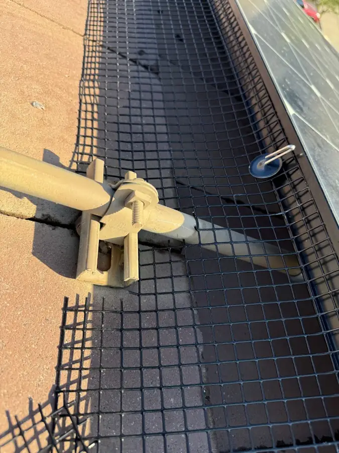 Close-up of pigeon-guard mesh clipped to the solar panel frame with no drilling into the panel